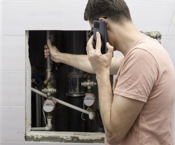 Man,Calls,Emergency,Plumber,Beside,Open,Utility,Hatch,,Hand,On